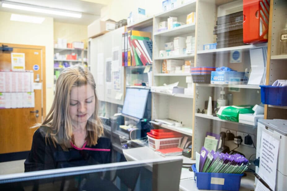 A pharmacist in a dispensary organising prescriptions